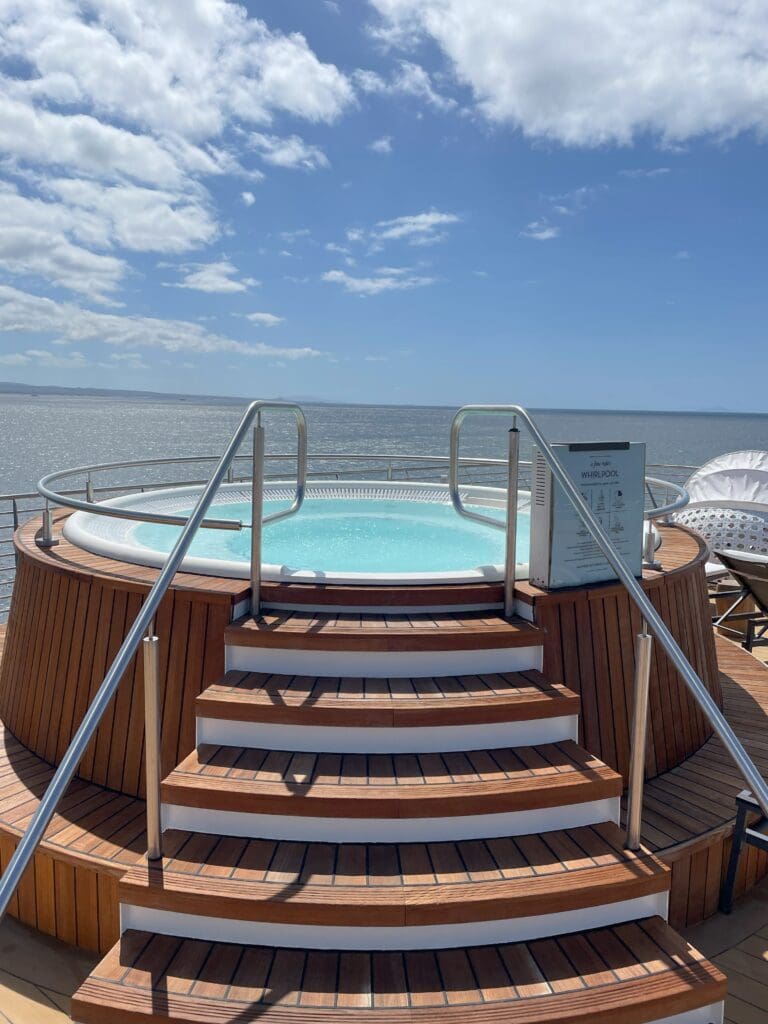 a hot tub on a deck with a body of water in the background