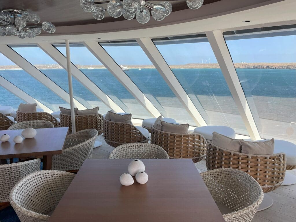 a room with a table and chairs and a view of the ocean