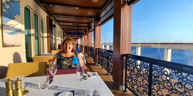 a woman sitting at a table with wine glasses on a deck