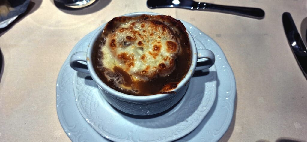 a cup of soup with melted cheese on top