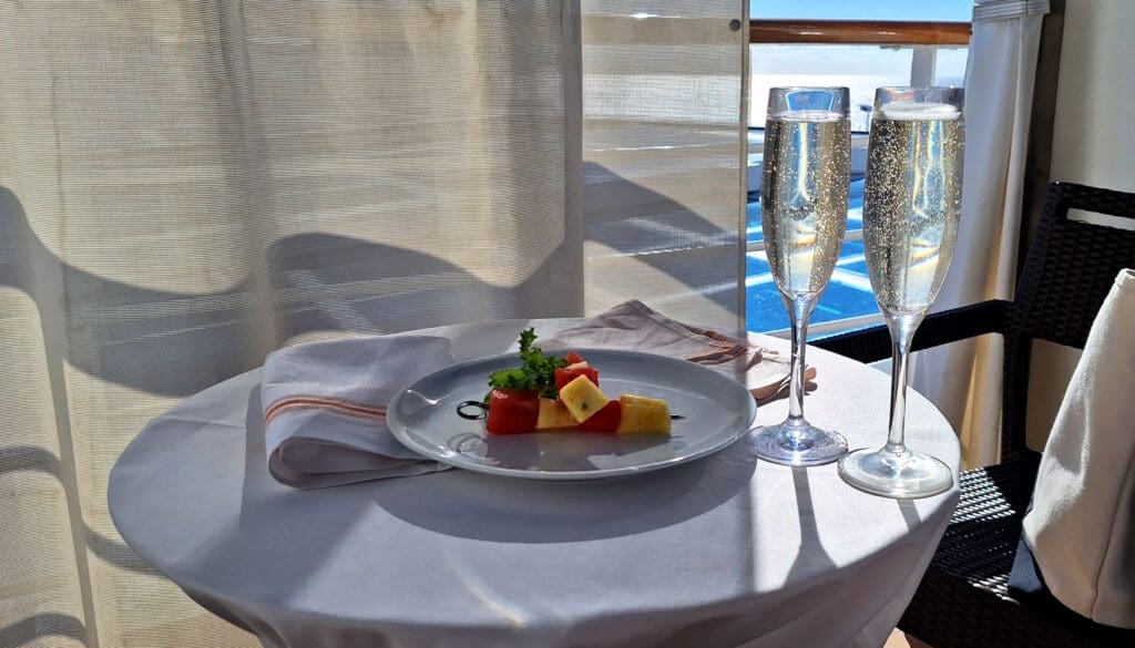 a plate of fruit and vegetables on a table with two champagne glasses