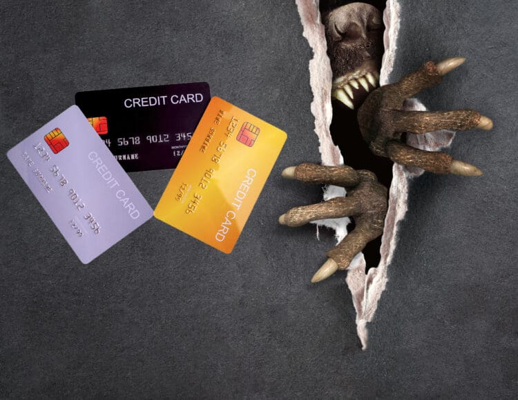 a monster hand with claws coming out of a hole with credit cards