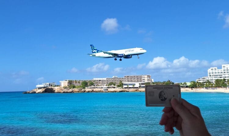 a hand holding a card and a plane flying over water