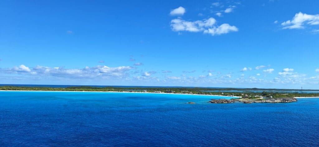 a blue water with a beach and land in the distance