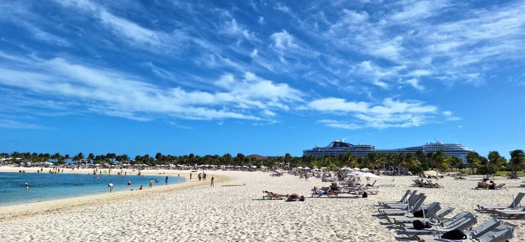 a beach with people and a cruise ship in the background