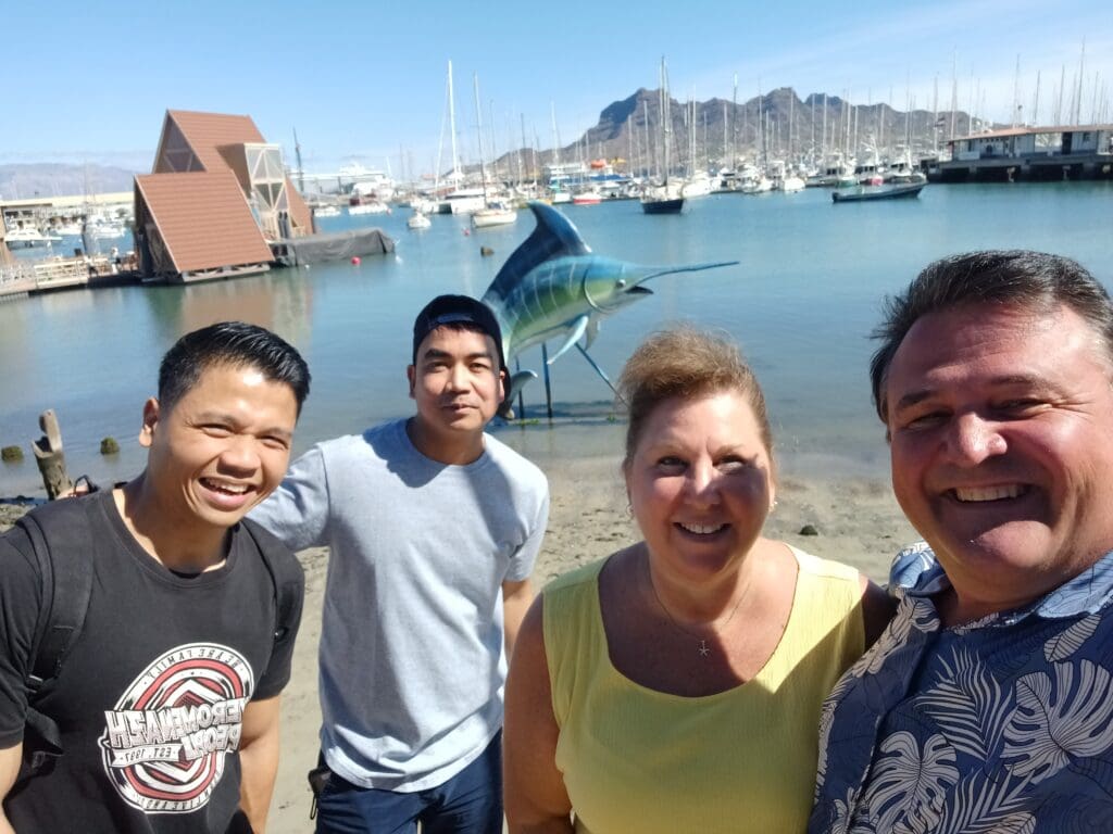 a group of people standing on a beach with a shark statue in the background