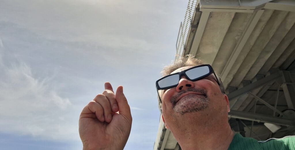 a man wearing sunglasses and pointing his finger up