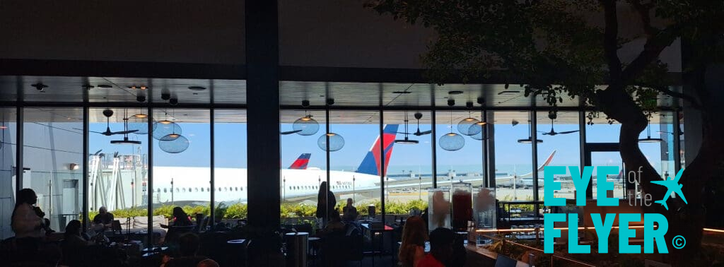 a window with people sitting at tables and a plane in the background