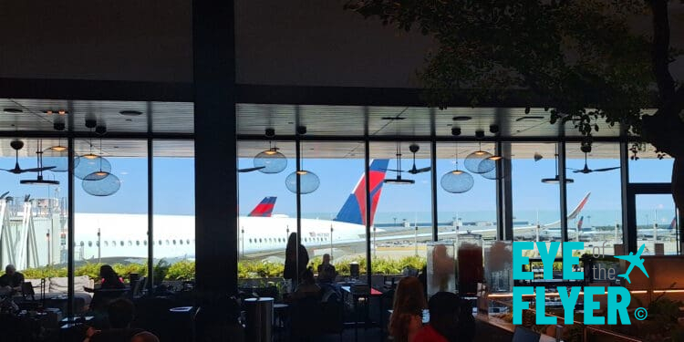 a window with people sitting at tables and a plane in the background