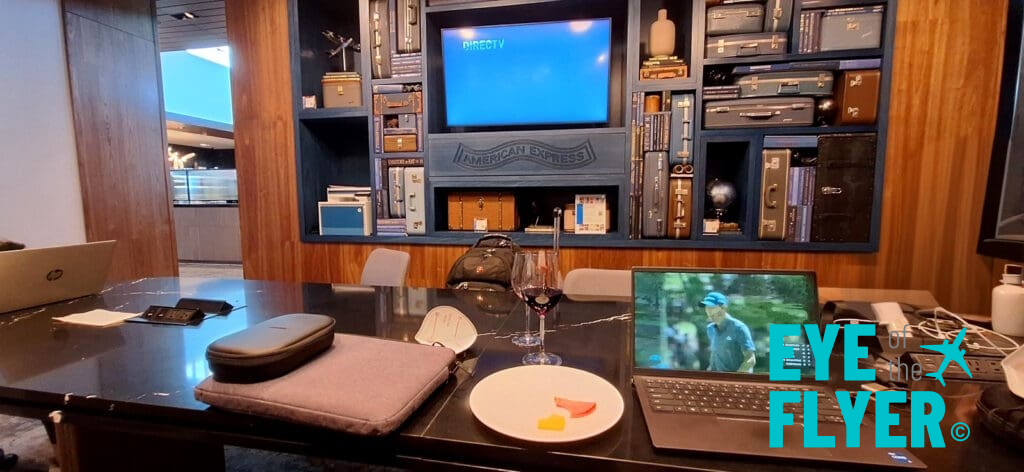 a laptop on a table with a glass of wine and a television