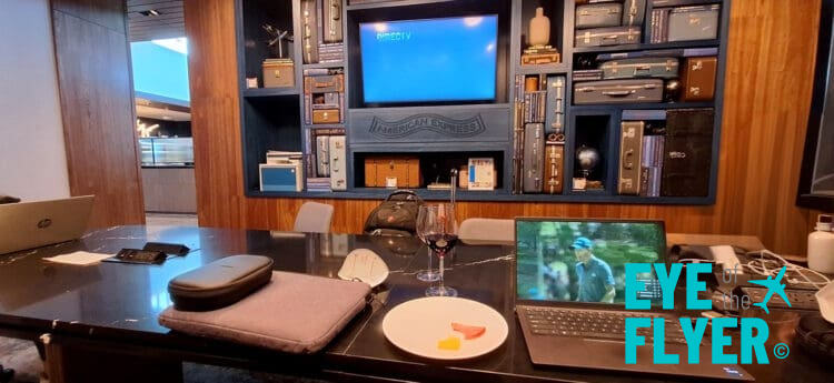 a laptop on a table with a glass of wine and a television