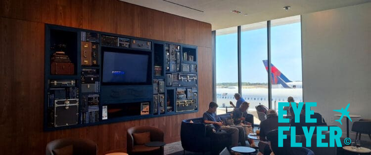 people sitting on a couch in a room with a television and a large window