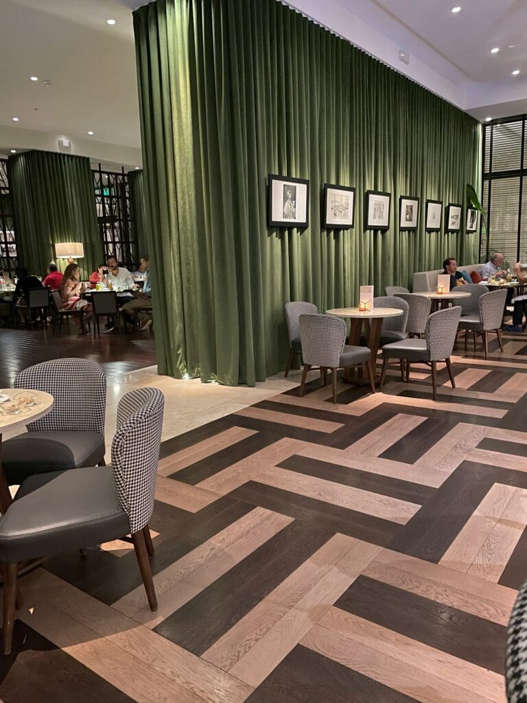 a room with green curtains and tables and chairs