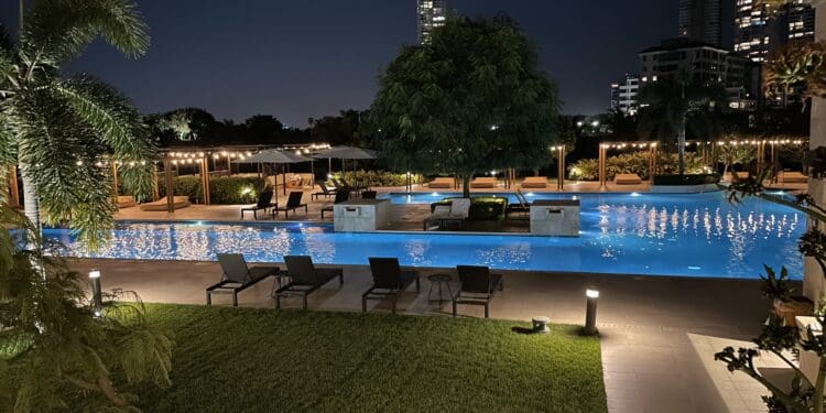 a pool with chairs and trees at night