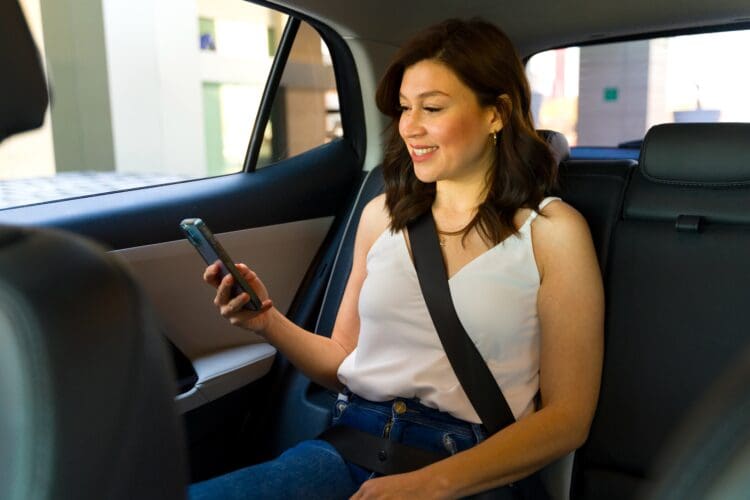 Female passenger uses her smartphone during a car ride, depicting modern transportation and the convenience of ride-sharing services