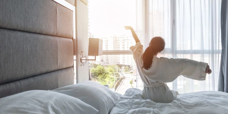a woman stretching on a bed in a luxury hotel room