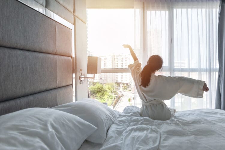 a woman stretching on a bed in a luxury hotel room