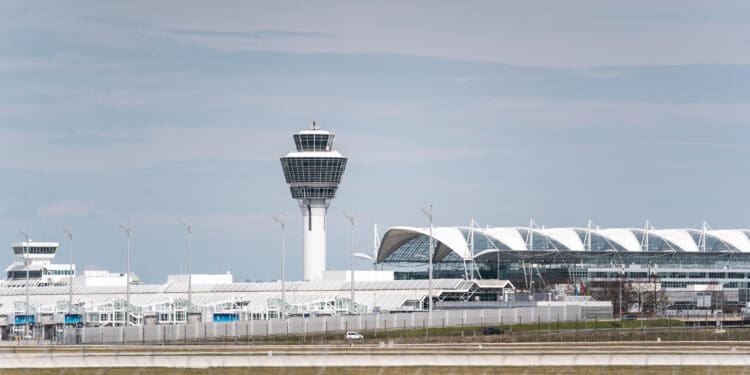 Munich, Germany – April 10, 2021: Tower and terminal at Munich Airport with the security fence in the foreground. Concept for tourism travel, vacation and flying