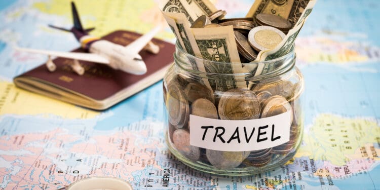 Travel budget concept. Travel money savings in a glass jar with compass, passport and aircraft toy on world map