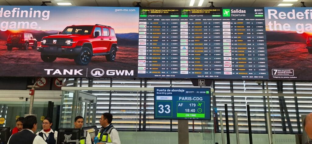 a man standing in front of a large screen with a picture of a car