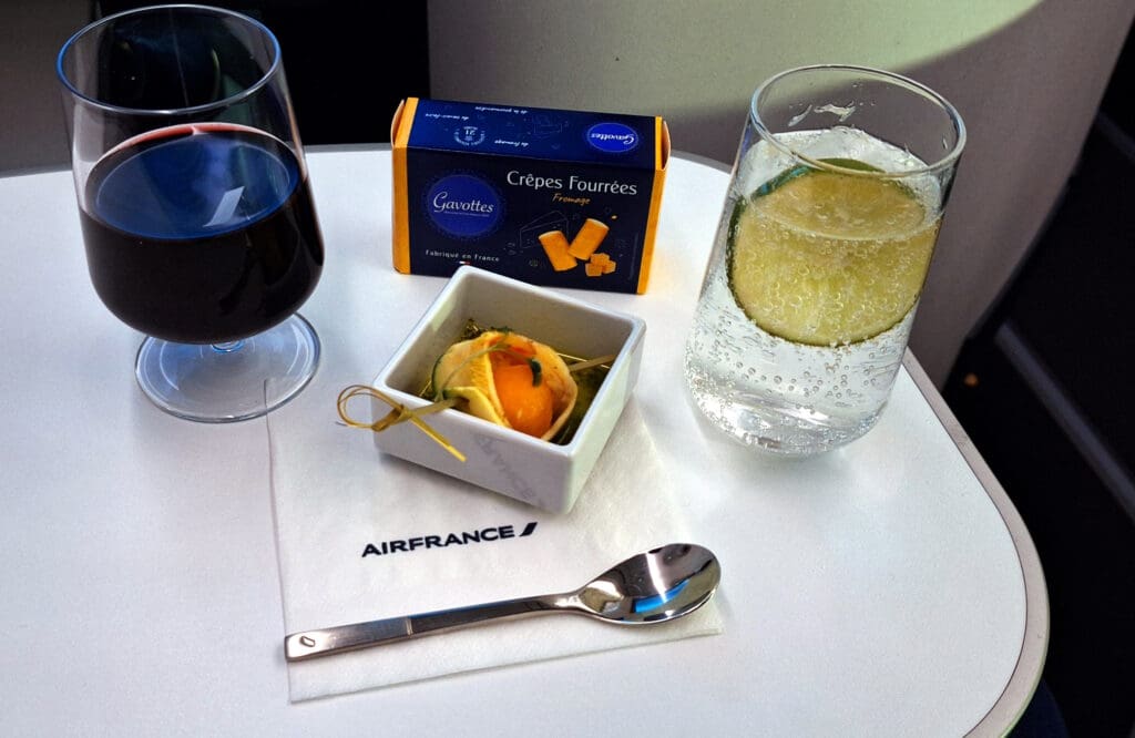 a small dish with an orange and a spoon next to a glass of liquid