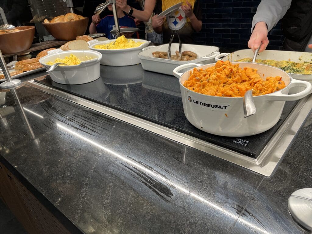 a group of people standing around a counter with food in bowls