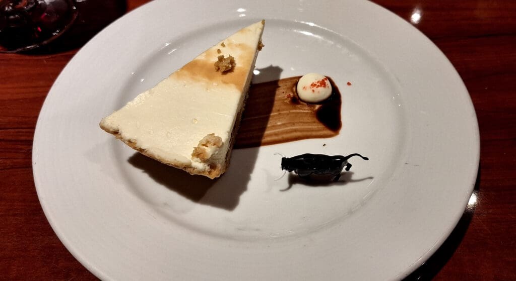 a piece of cheesecake with a toy mouse on it