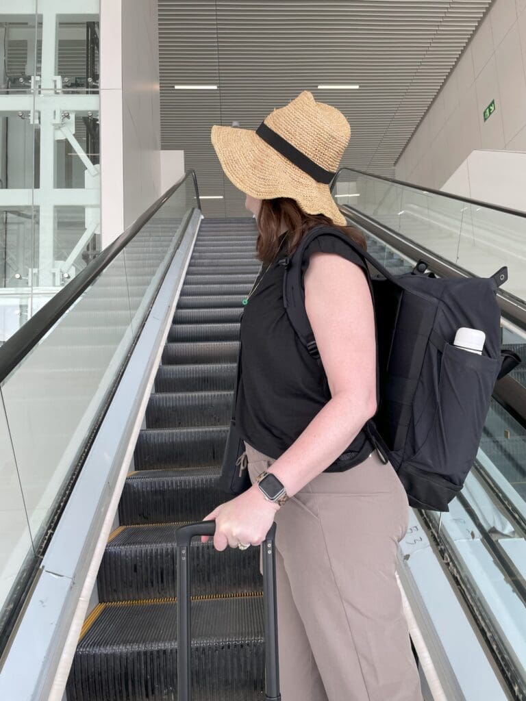 a woman with a hat and backpack on an escalator