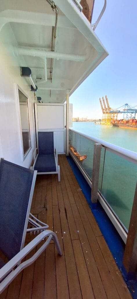 a deck with chairs and a boat in the water