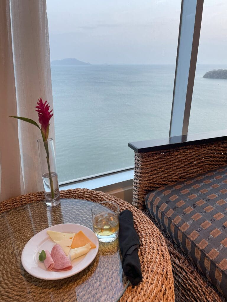 a table with food on it and a glass vase with a flower in front of a window