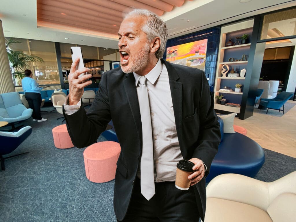 a man in a suit holding a phone and a cup of coffee