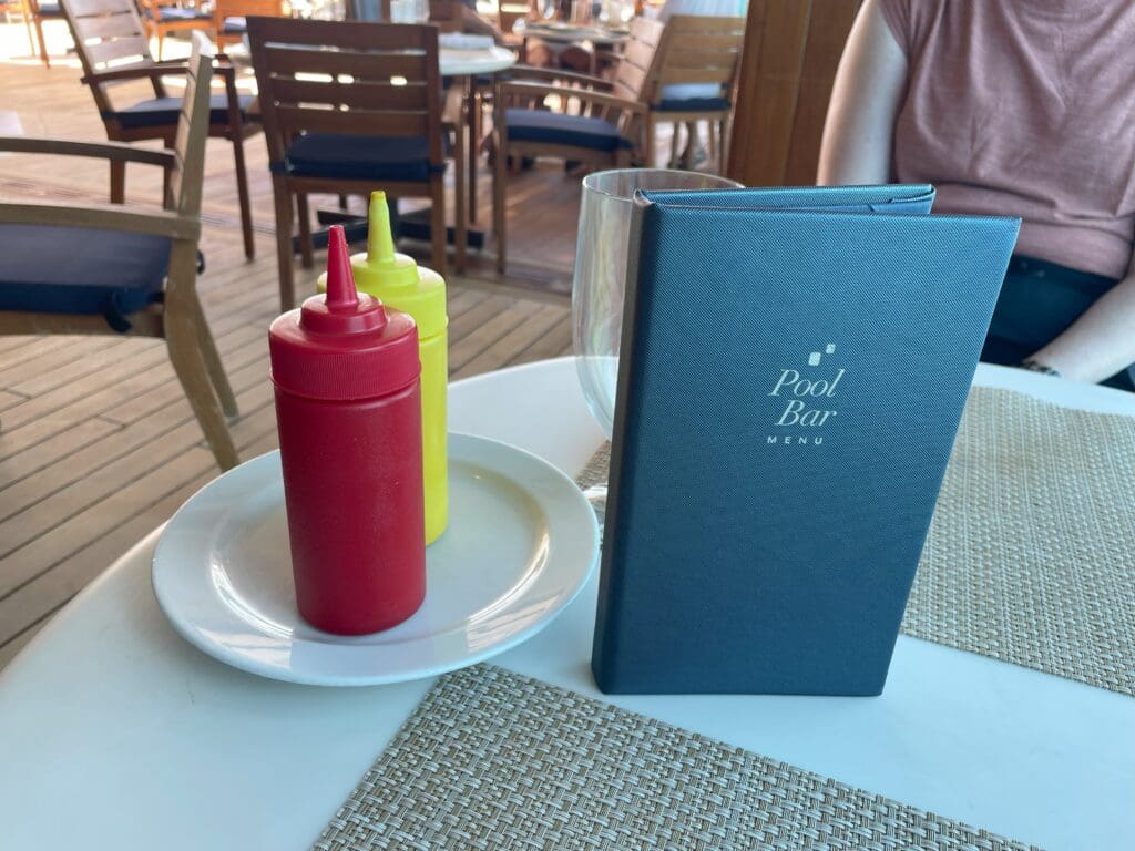 a table with a plate of ketchup and mustard bottles on it