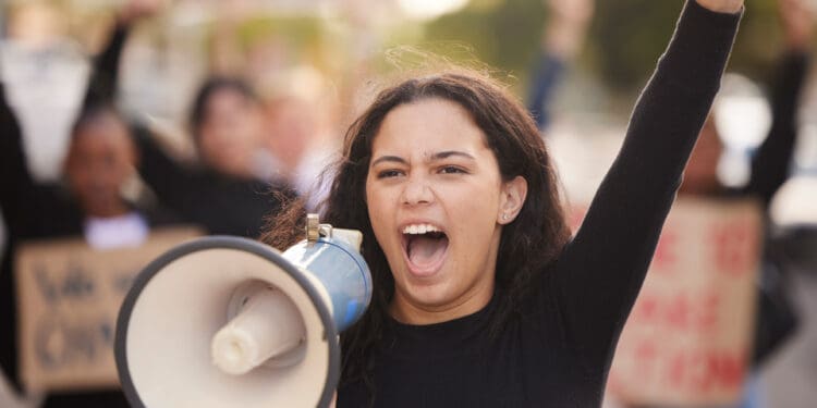 Megaphone, woman and people for gender equality, human rights or justice with freedom of speech in city street. Vote, protest and Mexico girl in crowd with voice for politics, angry broadcast or news