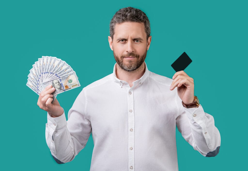 man paying with money card isolated on blue background. man paying with money card in studio. man paying with money card. photo of man paying with money card.