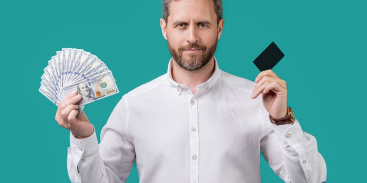 man paying with money card isolated on blue background. man paying with money card in studio. man paying with money card. photo of man paying with money card.