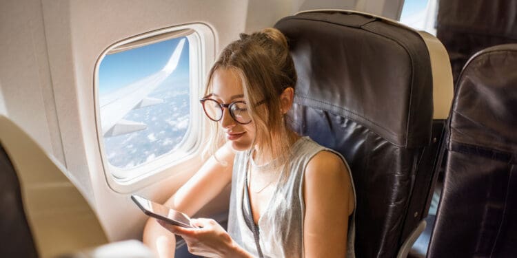 A young woman uses her phone on an airplane