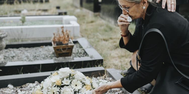 Old woman laying flowers on a grave