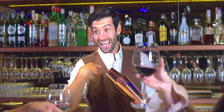 Professional bartender holds in hands steel shaker. talking to woman in bar