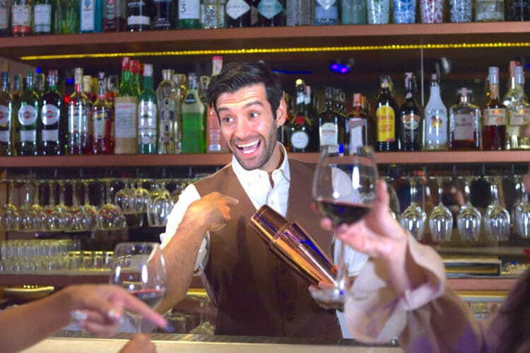 Professional bartender holds in hands steel shaker. talking to woman in bar