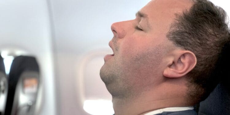 An airline passenger who might be sleeping or dead.