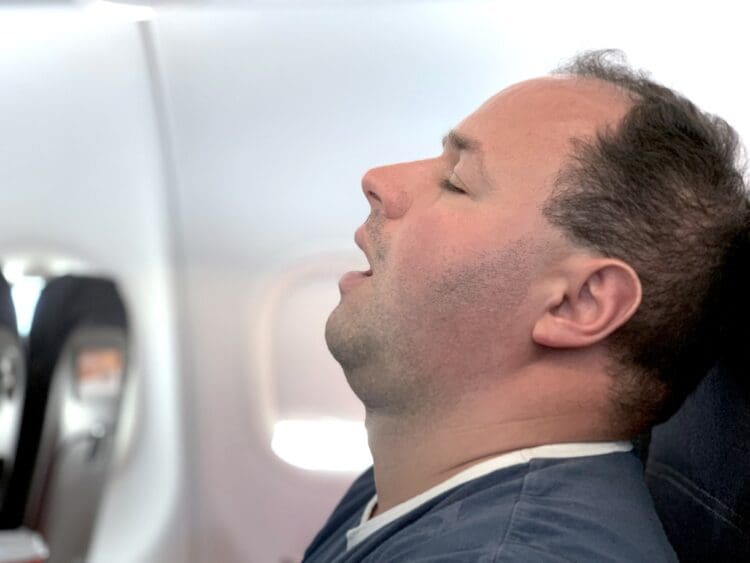 An airline passenger who might be sleeping or dead.