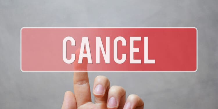 Cancel - hand pressing red transparent button on virtual touchscreen interface on grey background with copy space.