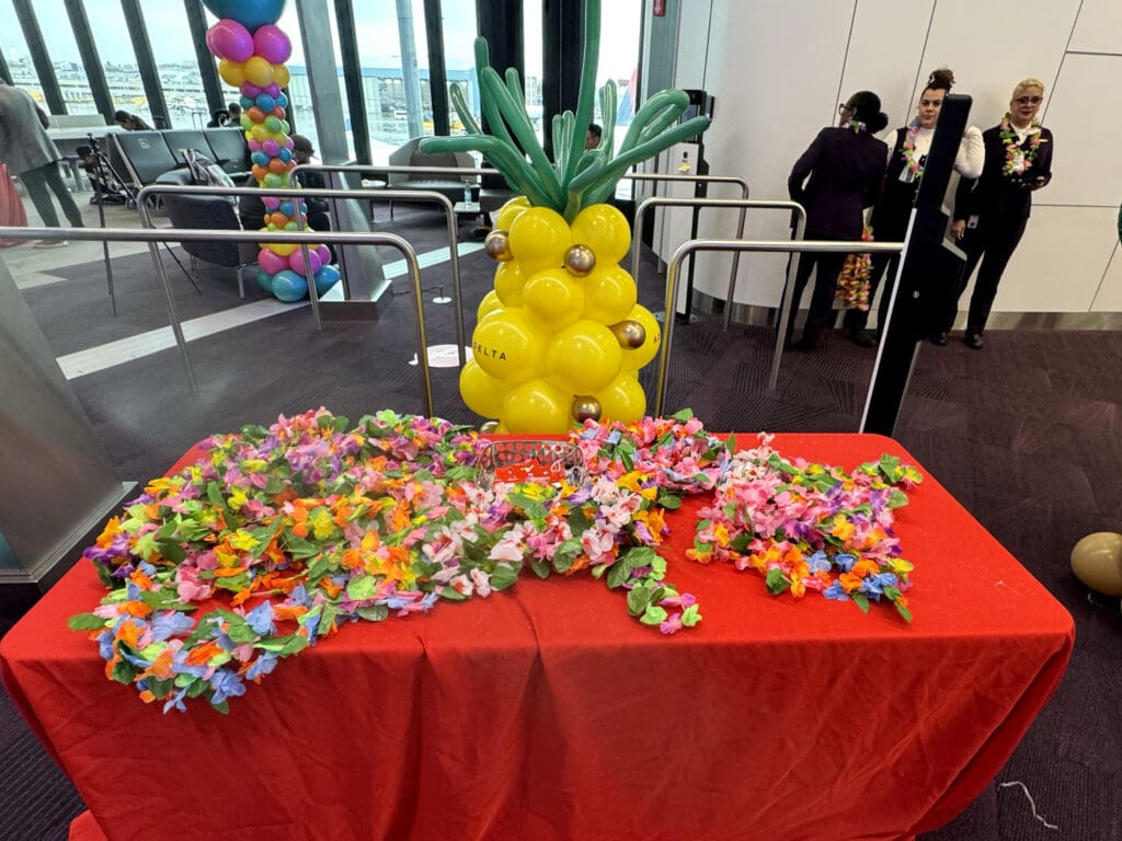 Imitation leis, Delta luggage tags, and a balloon pineapple are seen at gate E15 during the party for Delta Air Lines’ inaugural flight from Boston (BOS) to Honolulu (HNL) at Boston Logan International Airport on Thursday, November 21, 2024. (©Eye of the Flyer)