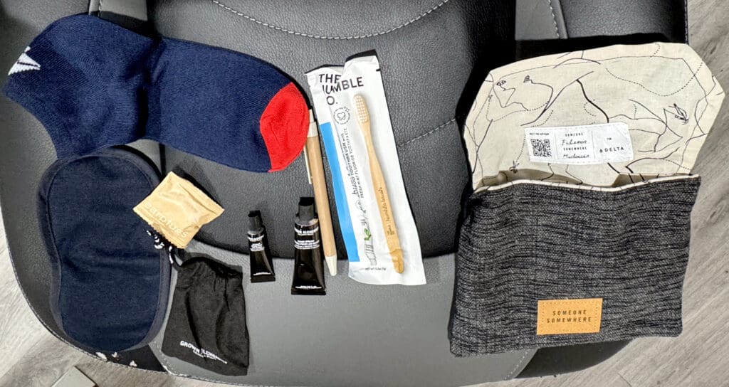 A Someone Somewhere amenity kit given to Delta Air Lines Premium Select customers includes an eye masks, socks, ear plugs, lip balm, hand lotion, a Delta-branded pen, and a toothbrush. 