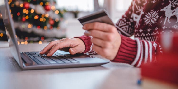 Women wearing red sweater shopping online and using credit card at home office