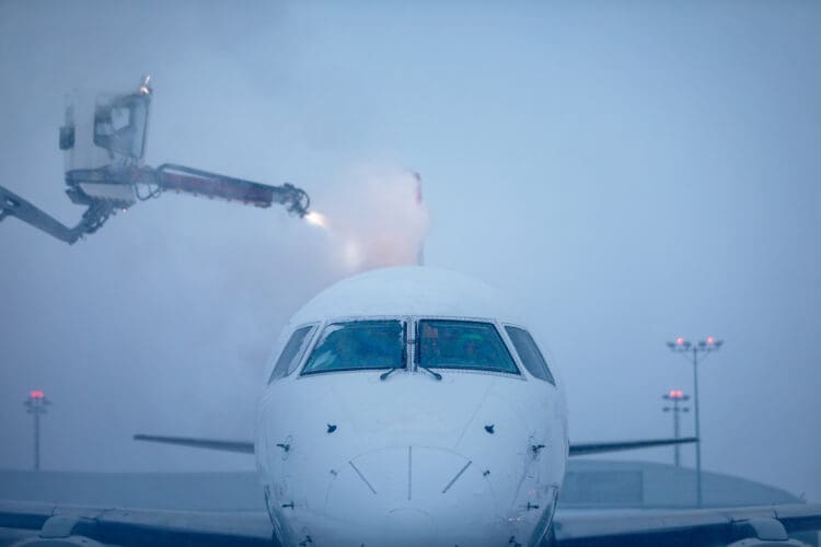 Deicing of airplane before flight. Winter frosty night and ground service at airport during snowfall.