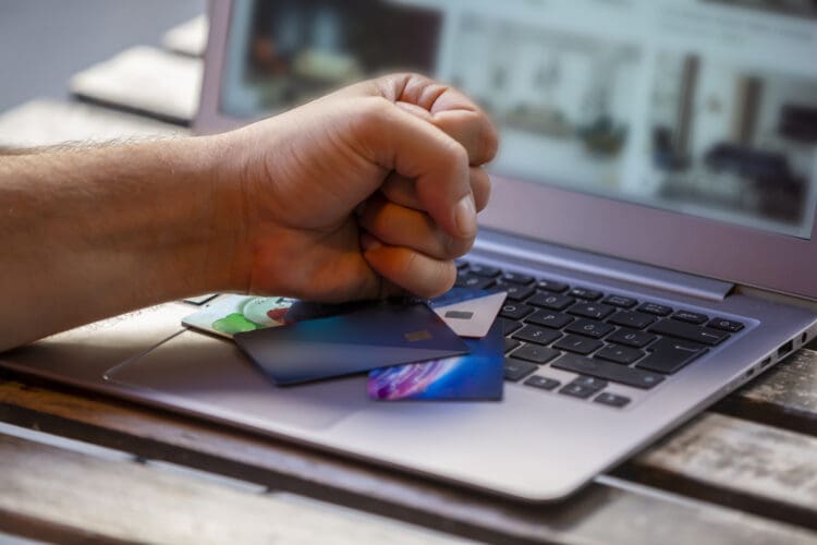 A person angrily hitting credit cards and the laptop with his fist