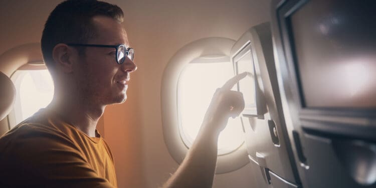 Man tapping an airliner seat's inflight entertainment screen