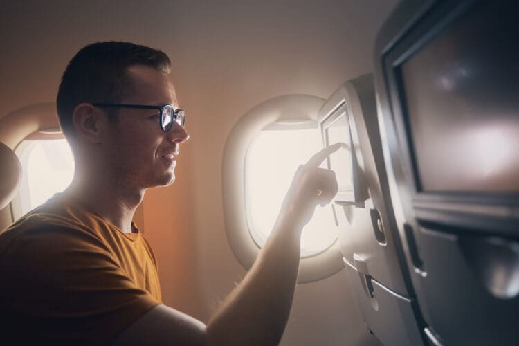 Man tapping an airliner seat's inflight entertainment screen