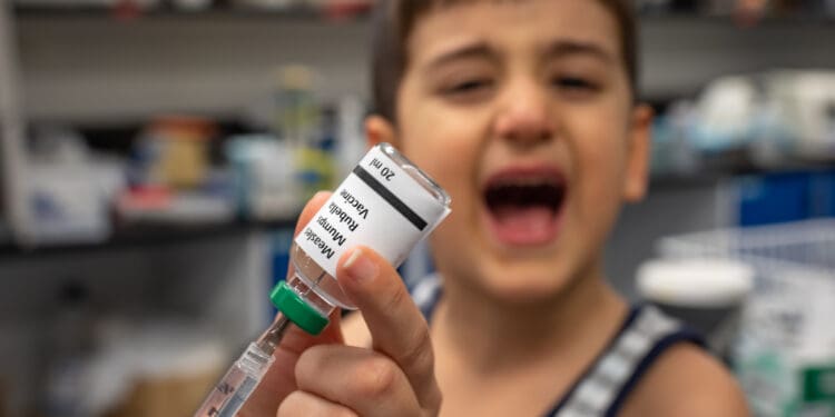 Doctor nurse is preparing a measles mumps and rubella vaccine and the kid is crying seeing the injection